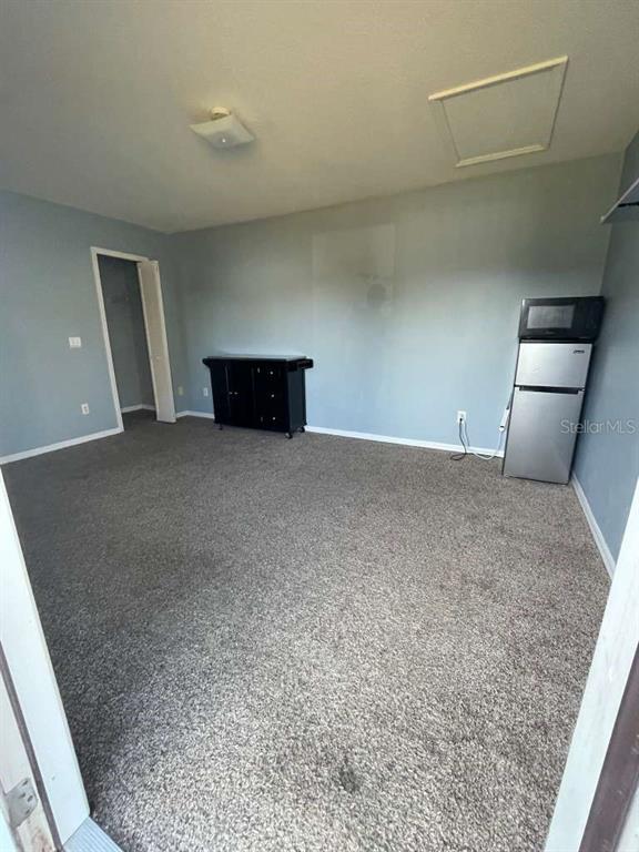 A room with gray walls, gray carpet, a black cabinet, and a small refrigerator — 241 CARIBBEAN DRIVE Front Unit, DAVENPORT, FL