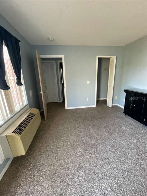 A bedroom with gray walls, carpeted flooring, an HVAC unit, and two open doorways — 241 CARIBBEAN DRIVE Front Unit, DAVENPORT, FL
