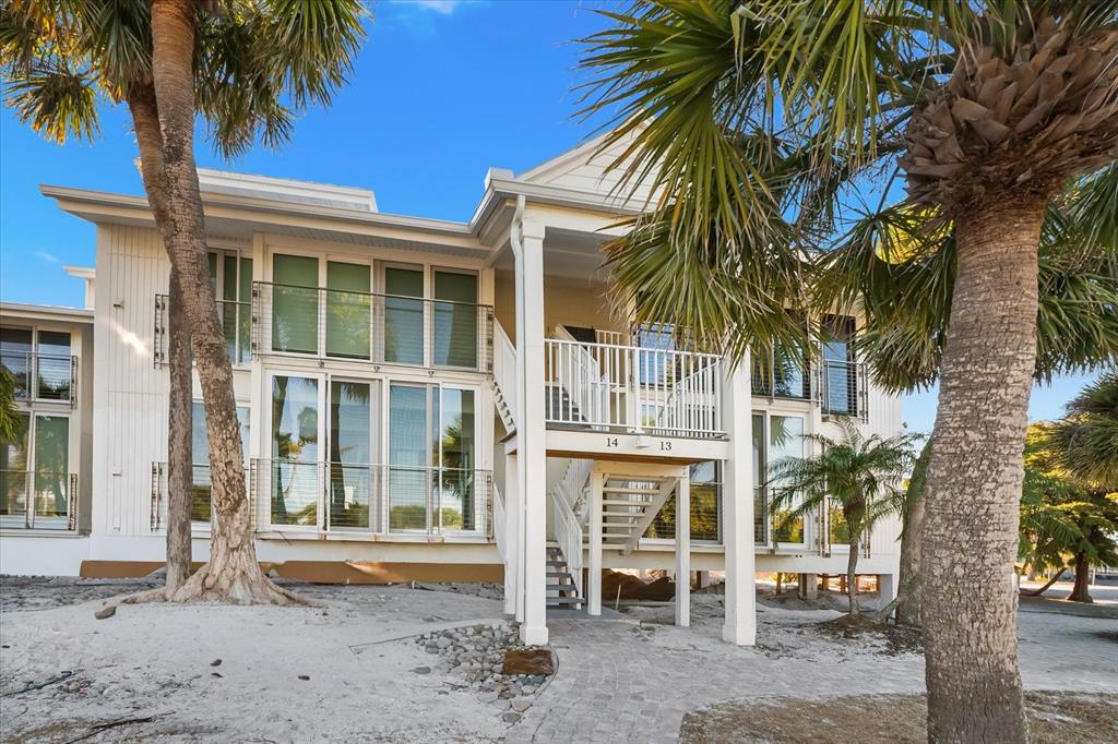 A two-story white building with large windows, balconies, and palm trees on a sandy lot — 5000 GASPARILLA ROAD UNIT 13A, BOCA GRANDE, FL