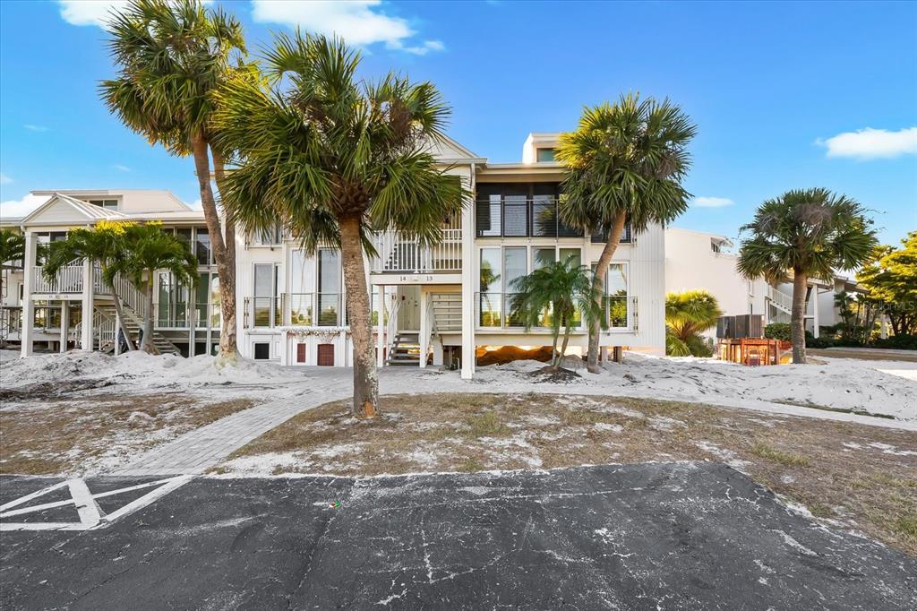 A multi-story beachside building with palm trees and a sandy ground level — 5000 GASPARILLA ROAD UNIT 13A, BOCA GRANDE, FL