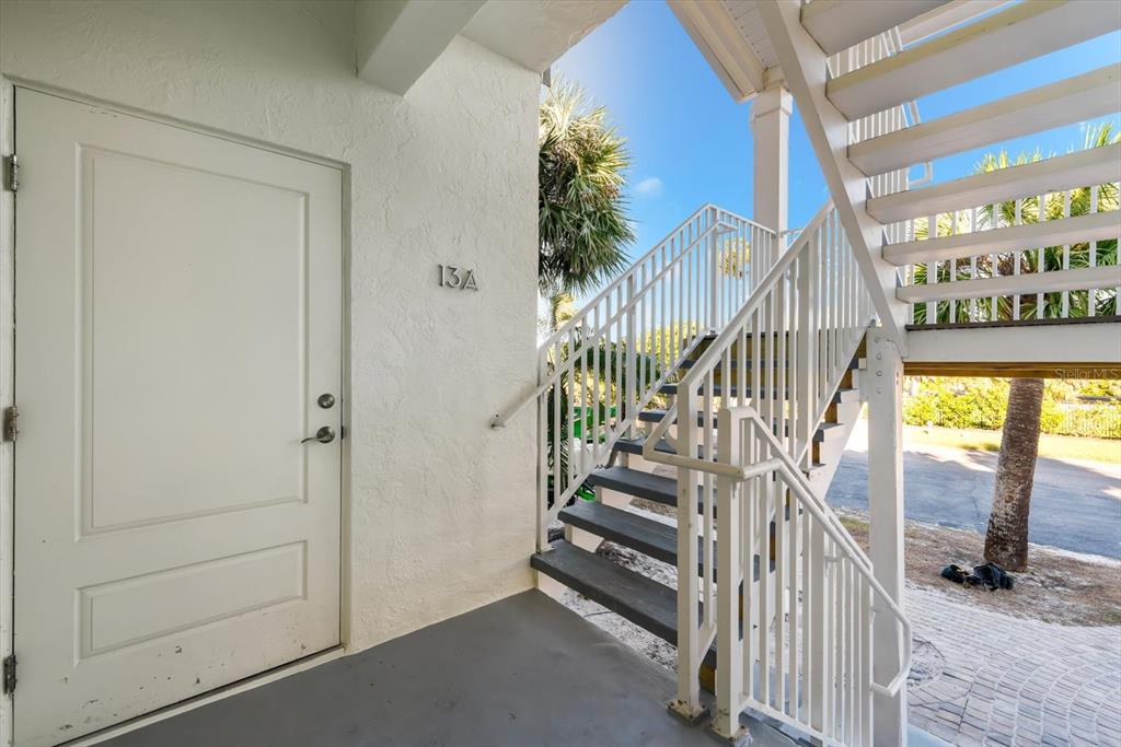 An exterior view shows a white door labeled 13A next to a metal staircase — 5000 GASPARILLA ROAD UNIT 13A, BOCA GRANDE, FL