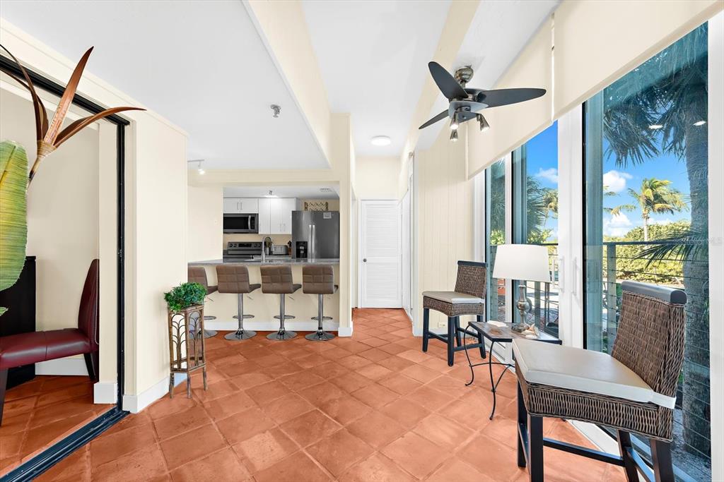 A sunroom with terracotta tile flooring features a breakfast bar and views of palm trees — 5000 GASPARILLA ROAD UNIT 13A, BOCA GRANDE, FL