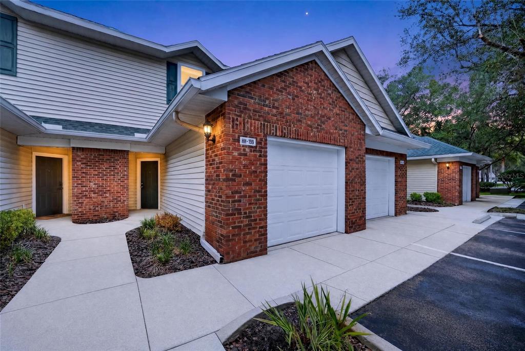 Exterior view of a multi-unit residential building with brick accents, white garage doors, and walkways — 13200 W NEWBERRY ROAD UNIT 199, NEWBERRY, FL