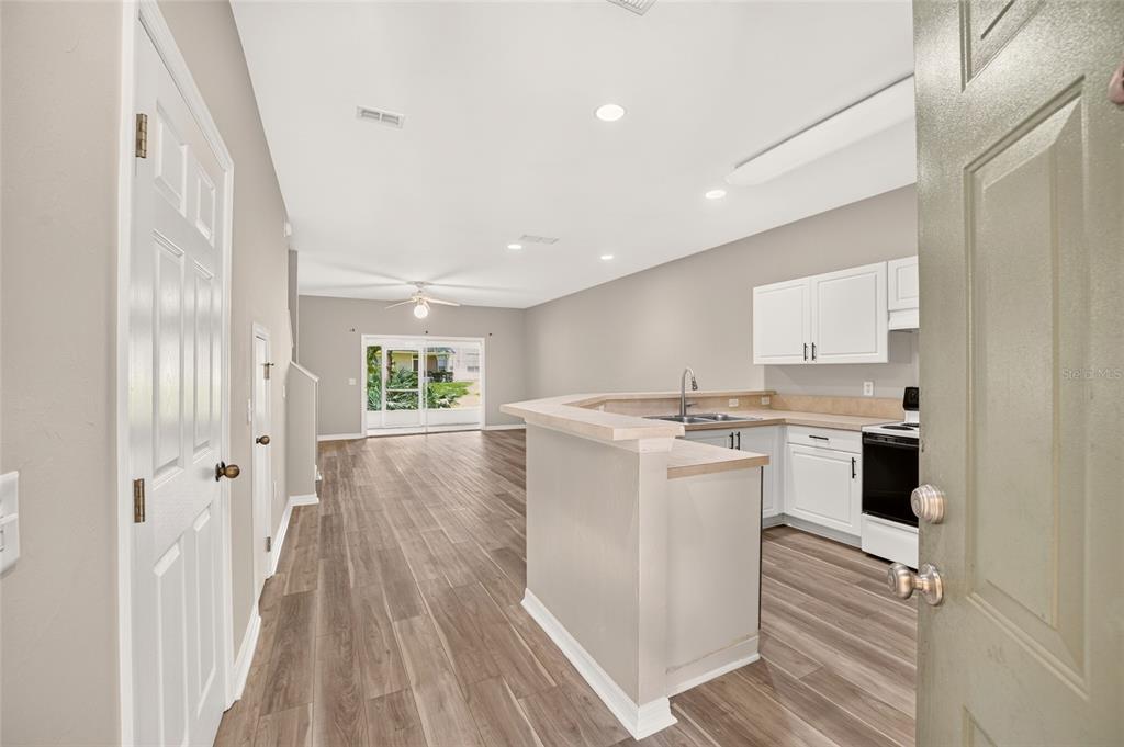 An open-concept kitchen and living area featuring wood-look flooring, white cabinets, and a breakfast bar — 13200 W NEWBERRY ROAD UNIT 199, NEWBERRY, FL