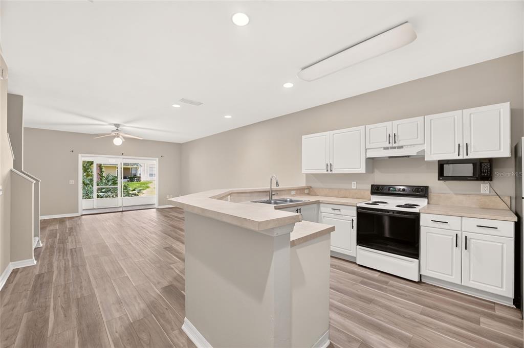 A kitchen with white cabinets and a breakfast bar opens to a living area — 13200 W NEWBERRY ROAD UNIT 199, NEWBERRY, FL