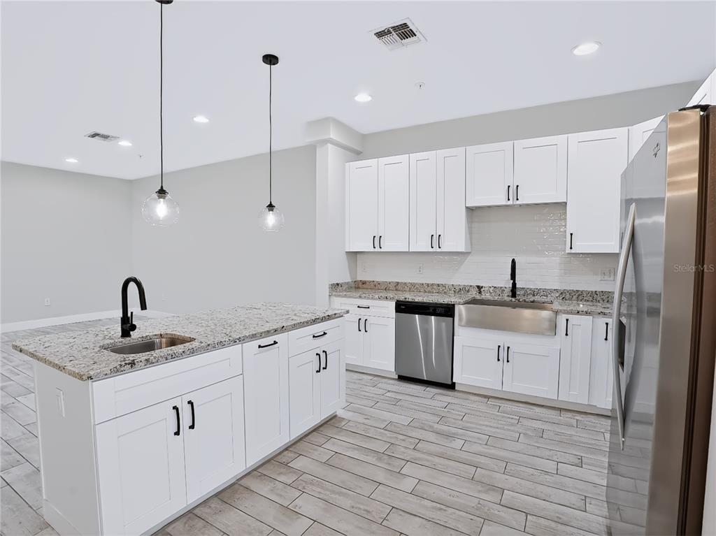 A modern kitchen features white cabinets, granite countertops, stainless steel appliances, and a central island — 2233 E KALEY AVENUE UNIT 6, ORLANDO, FL