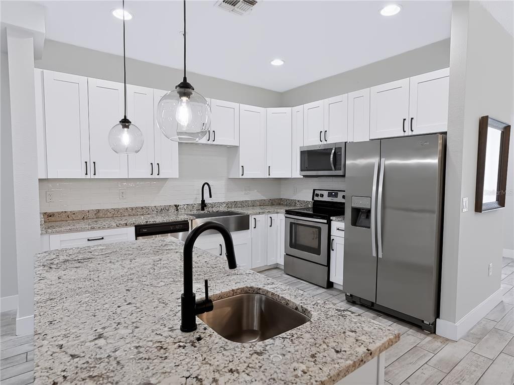 A modern kitchen features white cabinets, granite countertops, stainless steel appliances, and a center island — 2233 E KALEY AVENUE UNIT 6, ORLANDO, FL