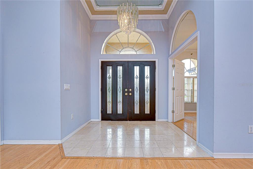 A foyer with tile flooring, a crystal chandelier, and double front doors with glass inserts — 3373 CRESCENT OAKS BOULEVARD, TARPON SPRINGS, FL