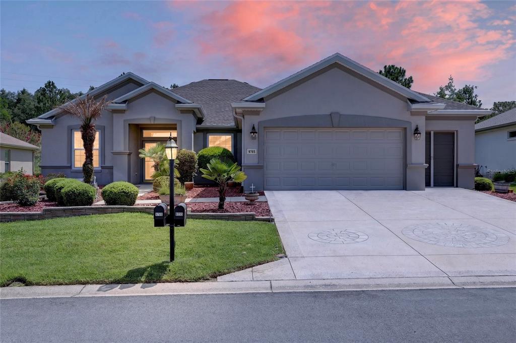 A single-story house with a gray stucco exterior, a two-car garage, and a landscaped front yard — 9785 SE 125TH LANE, SUMMERFIELD, FL