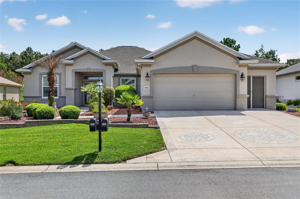A single-story suburban house with a beige stucco exterior, a two-car garage, and landscaping — 9785 SE 125TH LANE, SUMMERFIELD, FL