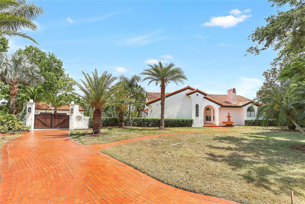 A white house with a red tile roof and a brick driveway sits among palm trees — 13124 FILLY COURT, WINDERMERE, FL