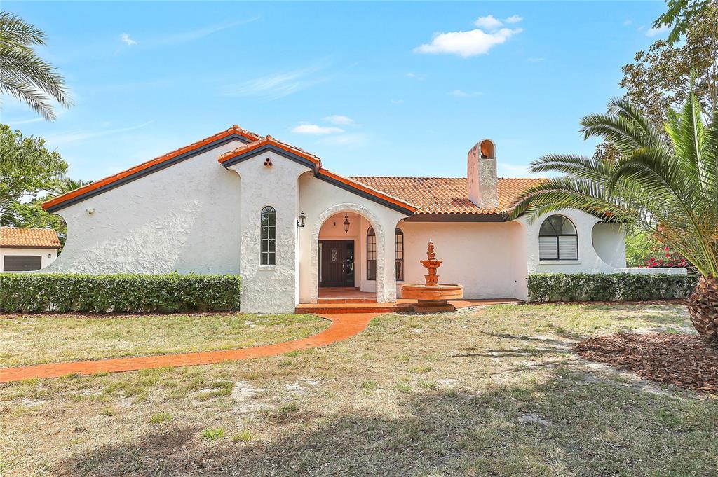 A single-story stucco house with a red tile roof, arched entryway, and a front fountain — 13124 FILLY COURT, WINDERMERE, FL