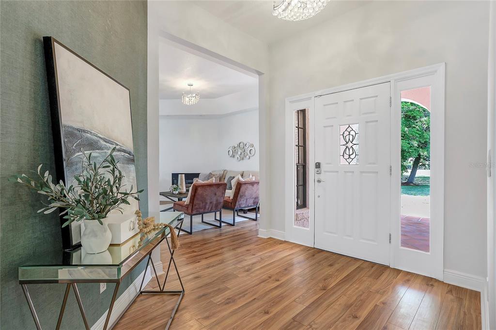 A bright entryway features wood-look flooring, a glass console table, and a white front door — 13124 FILLY COURT, WINDERMERE, FL