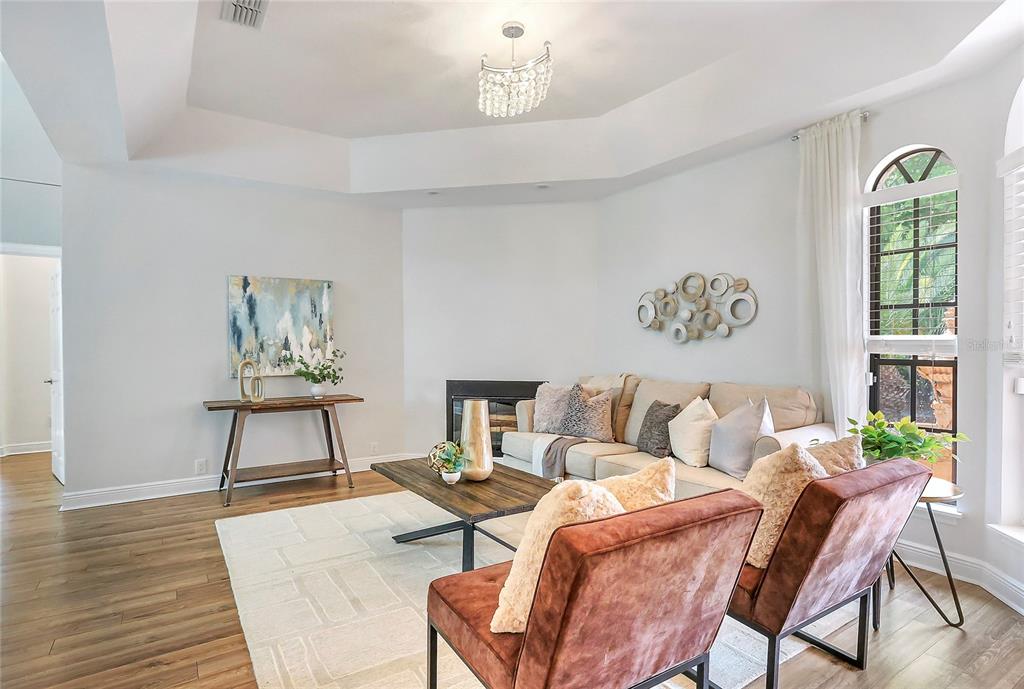 A living room features a fireplace, two brown armchairs, a sofa, and a crystal chandelier — 13124 FILLY COURT, WINDERMERE, FL