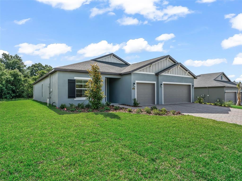 A single-story house with a gray stucco exterior, a three-car garage, and a front lawn — 6510 SW 180TH CIRCLE, DUNNELLON, FL