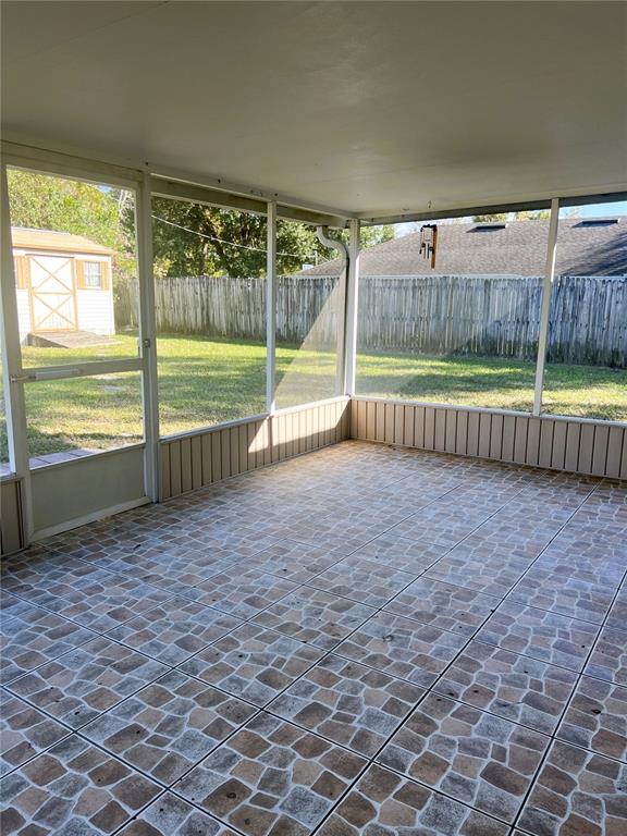 A screened-in porch features tiled flooring, a white ceiling, and a view of the backyard — 1706 HOWLAND BOULEVARD, DELTONA, FL