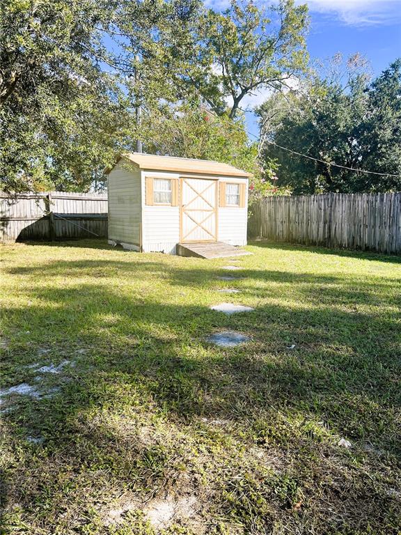 A small, light-colored storage shed sits in the center of a grassy backyard — 1706 HOWLAND BOULEVARD, DELTONA, FL