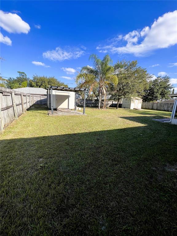 A grassy backyard features a wooden fence, a small shed, and a palm tree — 1706 HOWLAND BOULEVARD, DELTONA, FL