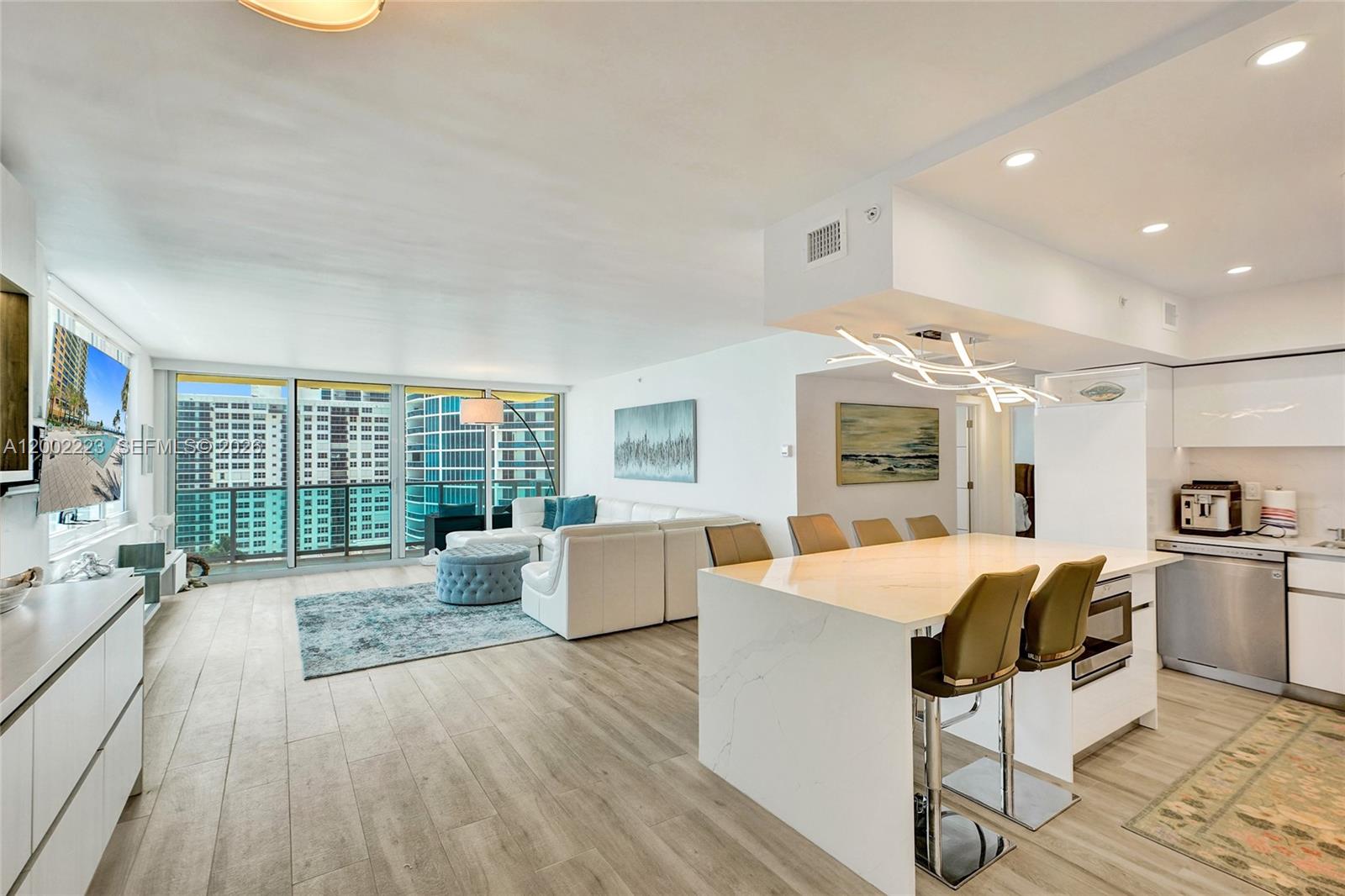 A modern open-concept living area features a white kitchen island, sectional sofa, and floor-to-ceiling windows — 2501 S Ocean Dr # 1211, Hollywood FL 33019, HOLLYWOOD, FL