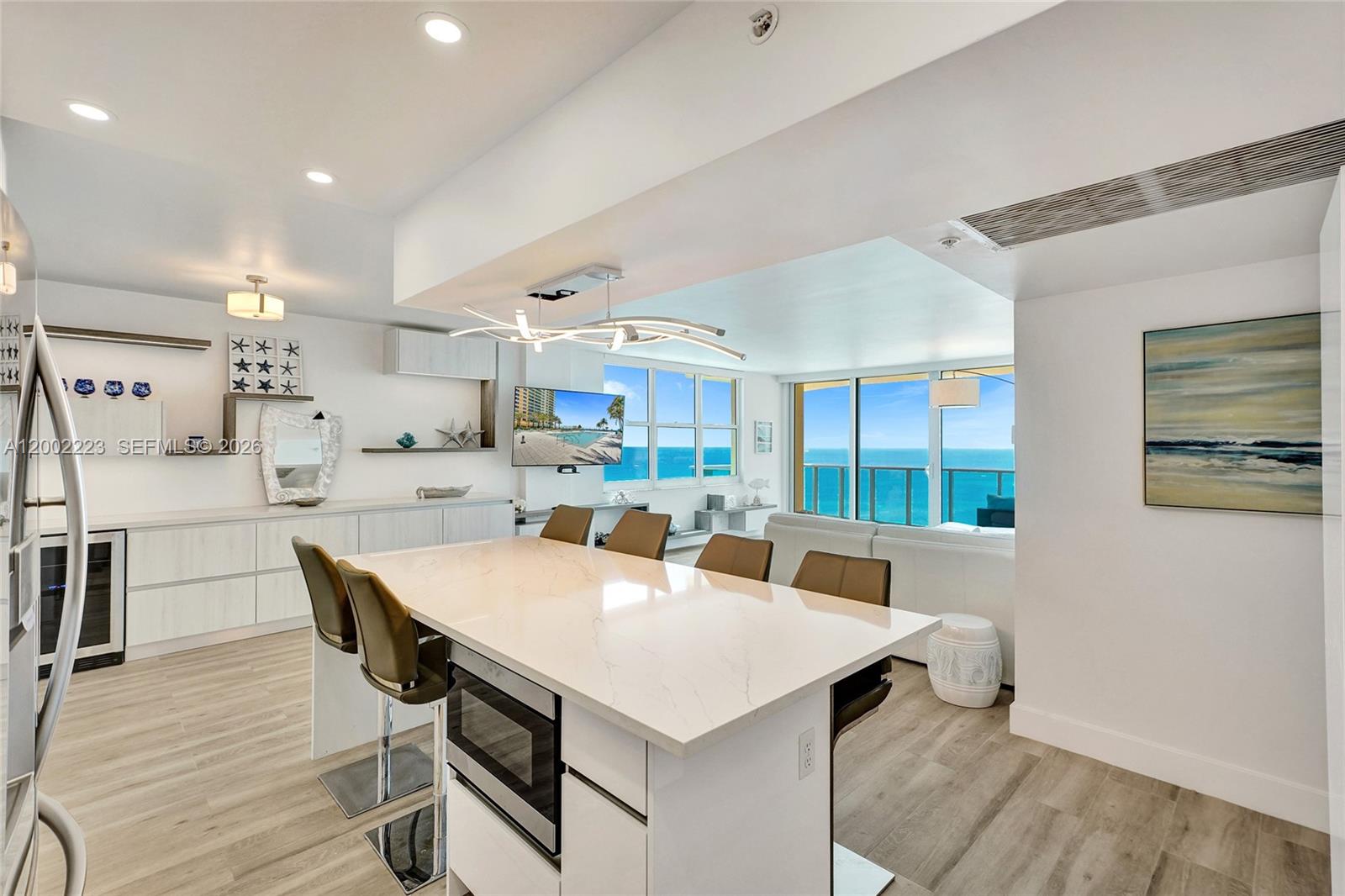 A modern kitchen with a white island and bar seating overlooks an oceanfront living area — 2501 S Ocean Dr # 1211, Hollywood FL 33019, HOLLYWOOD, FL