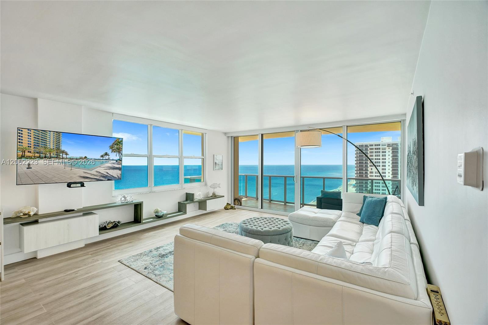 A bright living room features a white sectional sofa, wall-mounted television, and floor-to-ceiling ocean views — 2501 S Ocean Dr # 1211, Hollywood FL 33019, HOLLYWOOD, FL