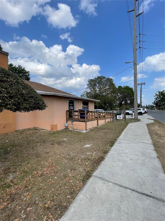 A peach-colored building with a wooden deck stands next to a sidewalk and utility pole — 2106 1ST STREET N, WINTER HAVEN, FL