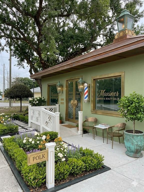 The exterior of a green building features a barber pole, a white railing, and landscaping — 2106 1ST STREET N, WINTER HAVEN, FL