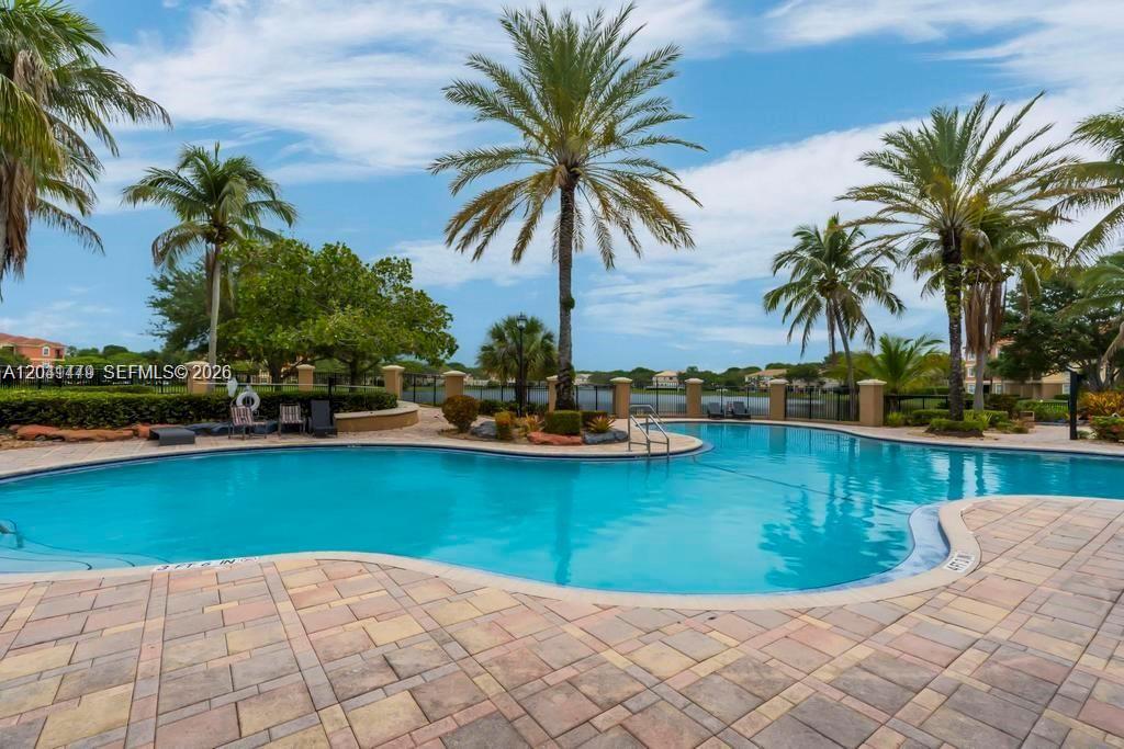 A swimming pool with a paved deck and palm trees under a blue sky — 4506 SW 160th Ave # 1116, Miramar FL 33027, MIRAMAR, FL