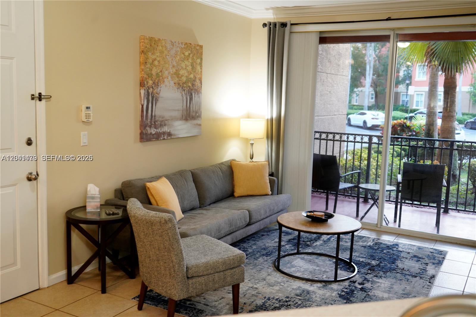 A living room features a grey sofa, a round coffee table, and a sliding glass door — 4506 SW 160th Ave # 1116, Miramar FL 33027, MIRAMAR, FL