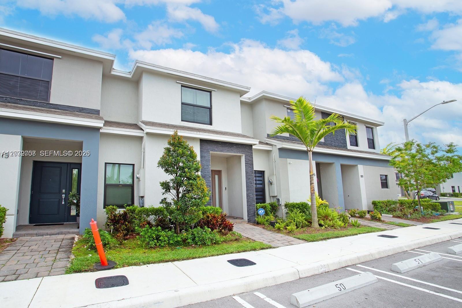 A multi-story townhouse exterior with a gray facade, stone accents, and a small front garden — 109 NE 3rd Ct, Florida City FL 33034, FLORIDA CITY, FL