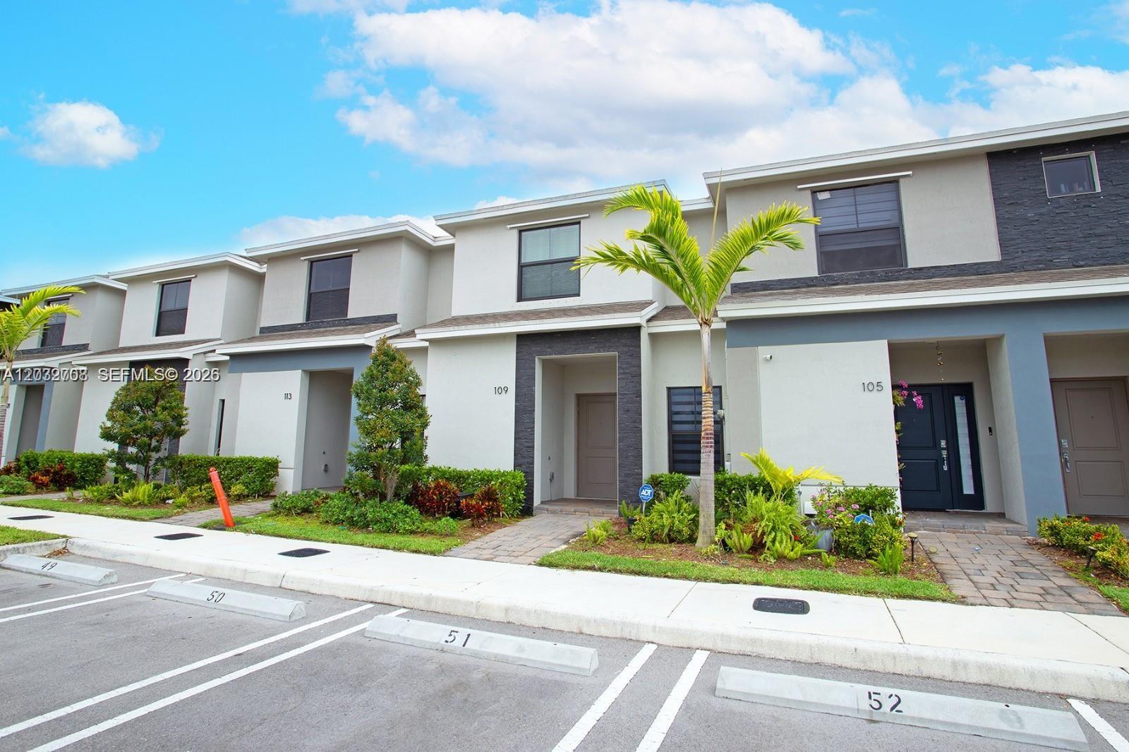 A row of modern two-story townhouses features gray and white facades with designated parking spaces — 109 NE 3rd Ct, Florida City FL 33034, FLORIDA CITY, FL