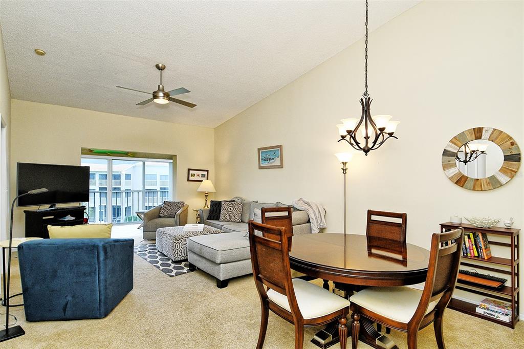 A living and dining area with carpeted floors, a ceiling fan, and a sliding glass door — 9610 CLUB SOUTH CIRCLE UNIT 4302, SARASOTA, FL
