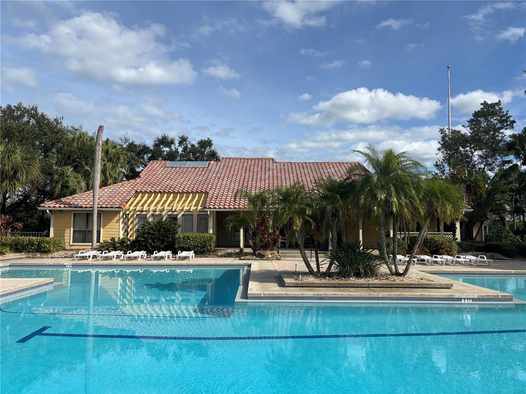 A swimming pool sits in front of a single-story building with a tiled roof — 11901 4TH STREET N UNIT 7107, ST PETERSBURG, FL