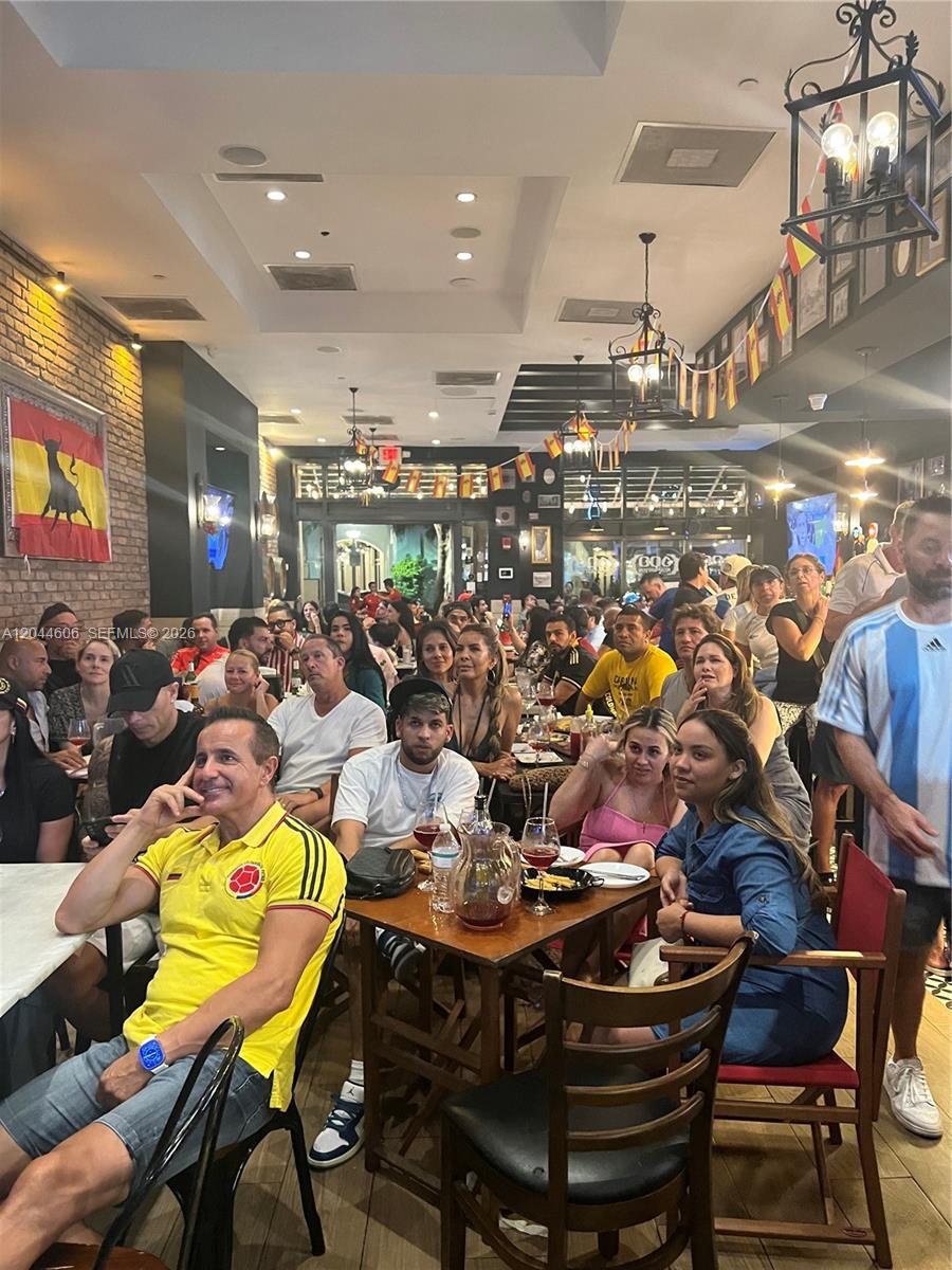 A crowded restaurant interior features brick walls, hanging flags, and patrons seated at tables — 3252 NE 1ST AVE, Miami FL 33137, MIAMI, FL