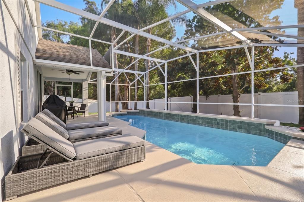 A screened-in patio features a swimming pool with a tiled wall and lounge chairs — 6847 BOUGANVILLEA CRESCENT DRIVE, ORLANDO, FL