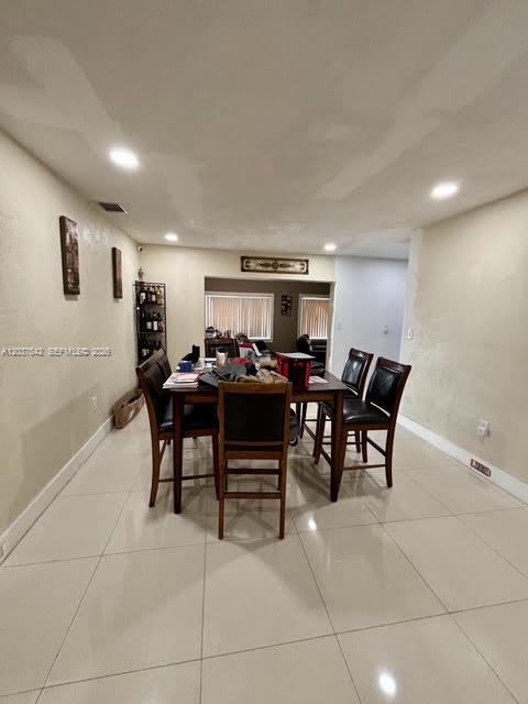 A dining room features a dark wood table and chairs on light-colored tile flooring — 7461 Douglas St, Hollywood FL 33024, HOLLYWOOD, FL