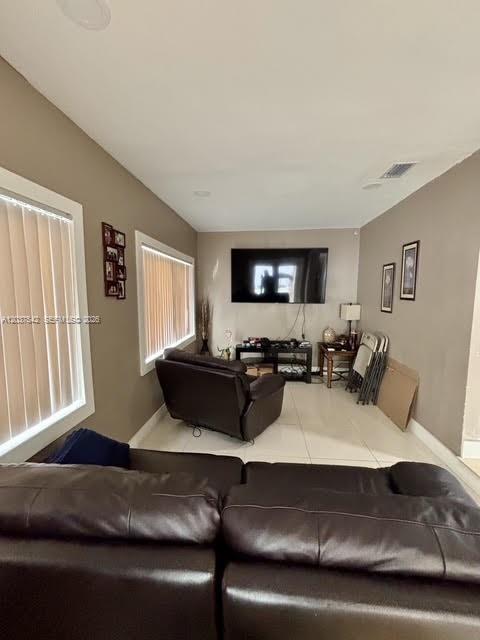 A living room features a dark leather sofa, a matching recliner, and a wall-mounted television — 7461 Douglas St, Hollywood FL 33024, HOLLYWOOD, FL
