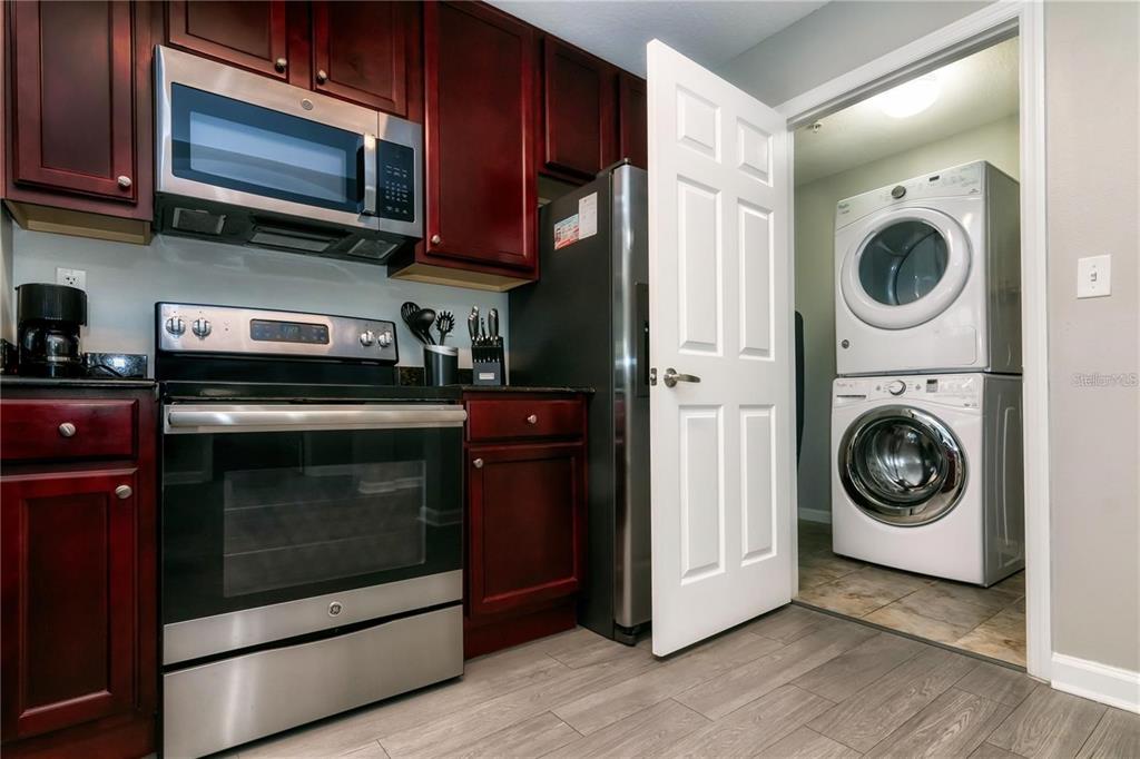 A kitchen with dark wood cabinets, stainless steel appliances, and an adjacent laundry closet — 14501 GROVE RESORT AVENUE UNIT 1728, WINTER GARDEN, FL