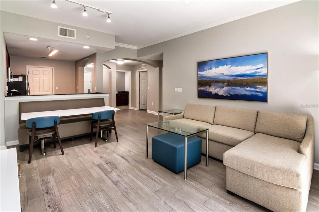 A living room with light wood floors, a beige sectional sofa, and a dining area — 14501 GROVE RESORT AVENUE UNIT 1728, WINTER GARDEN, FL
