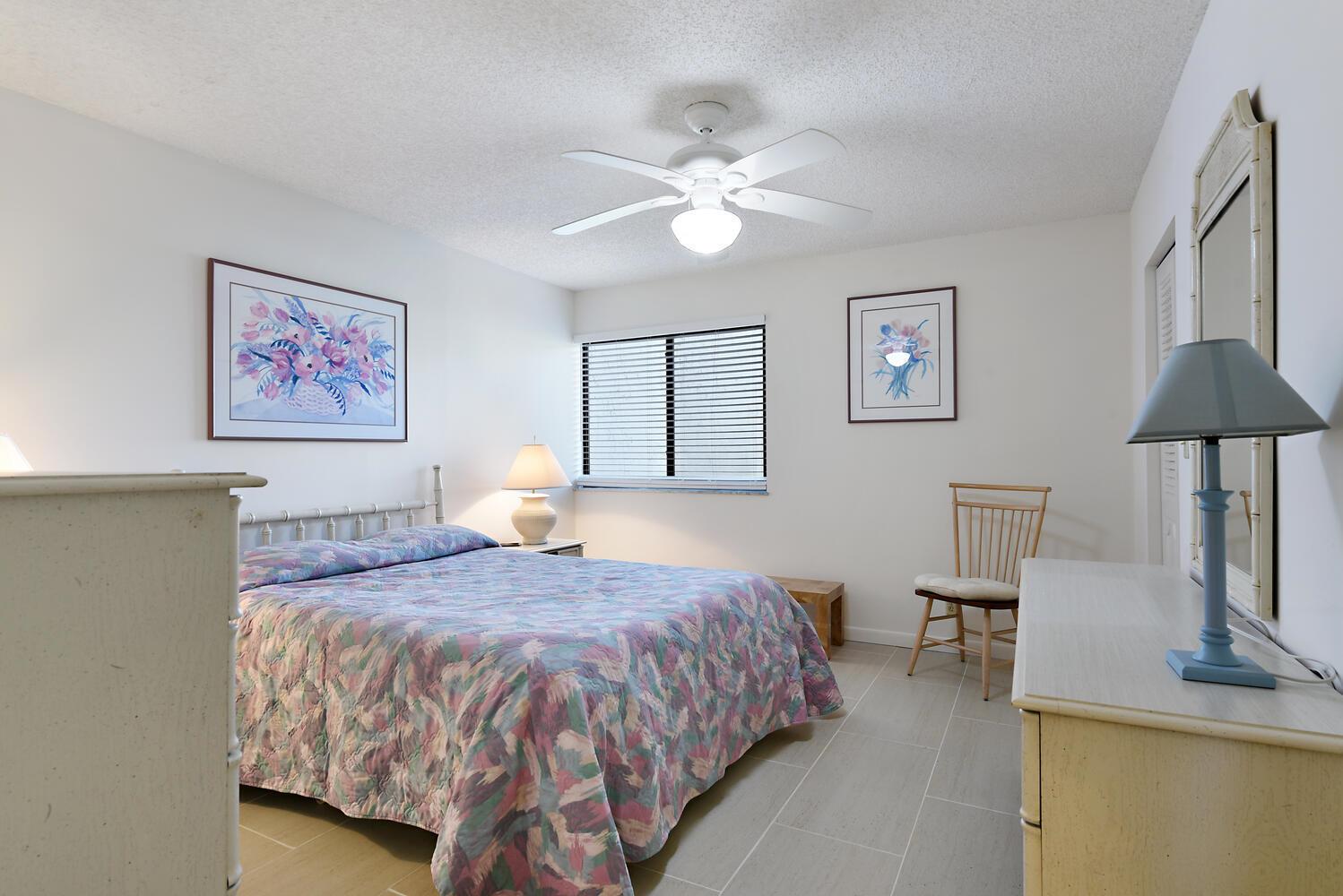 A bedroom features a floral quilt on the bed, a ceiling fan, and tile flooring — 1605 S Us Highway 1 # 106, Jupiter FL 33477, JUPITER, FL