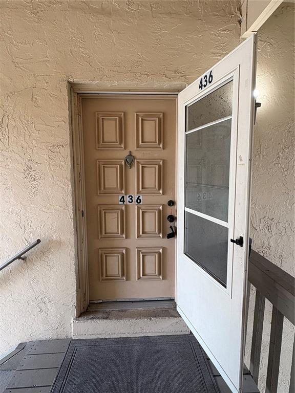 A beige front door with a storm door stands at the top of a small staircase — 436 WINDMEADOWS STREET UNIT 436, ALTAMONTE SPRINGS, FL