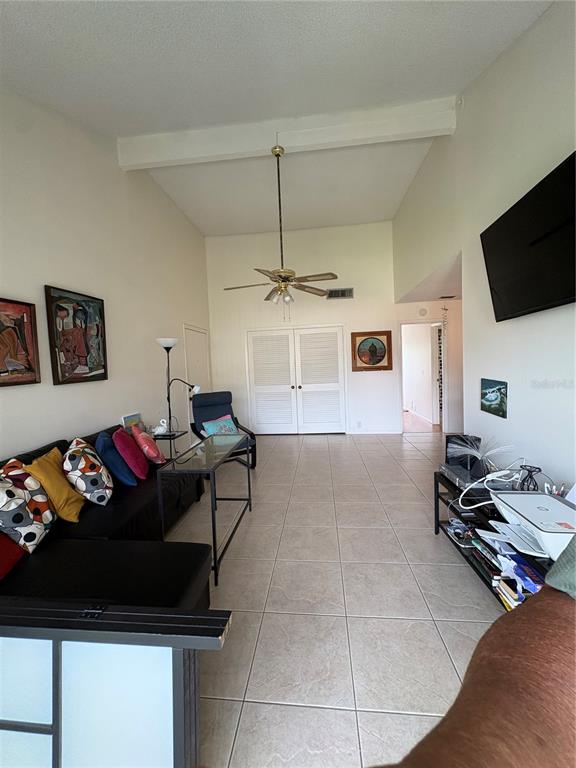 A living room features vaulted ceilings, tile flooring, a ceiling fan, and a wall-mounted television — 436 WINDMEADOWS STREET UNIT 436, ALTAMONTE SPRINGS, FL
