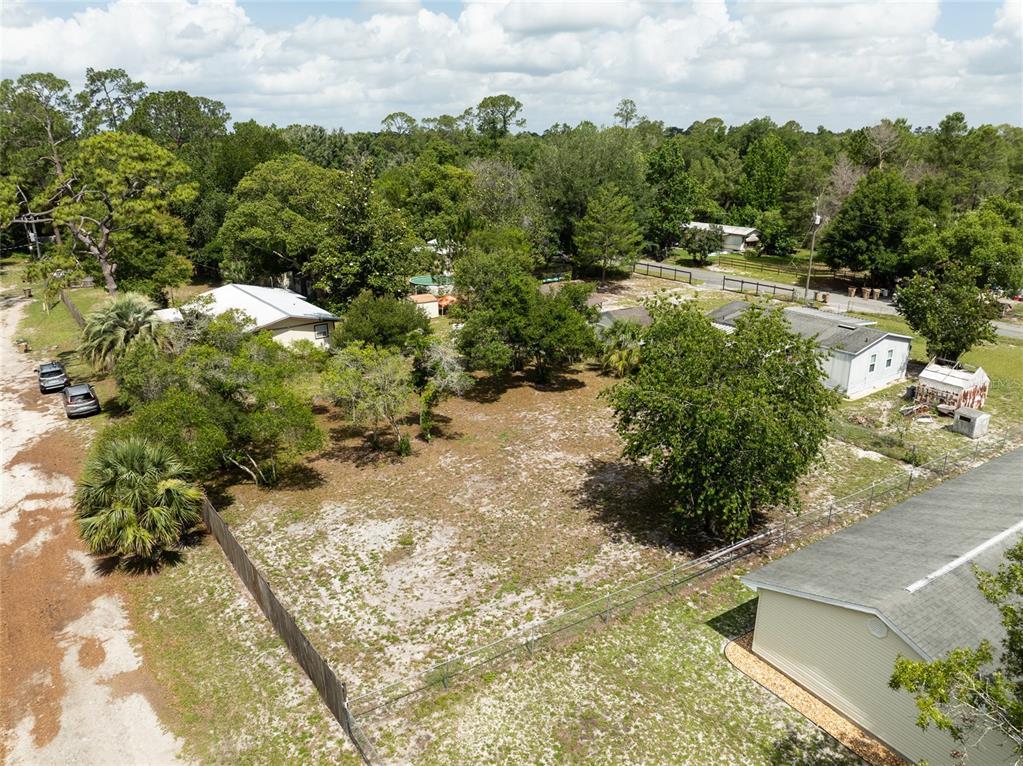 An aerial view shows a vacant lot surrounded by trees, fences, and neighboring houses — 27751 LUELLA AVENUE, PAISLEY, FL