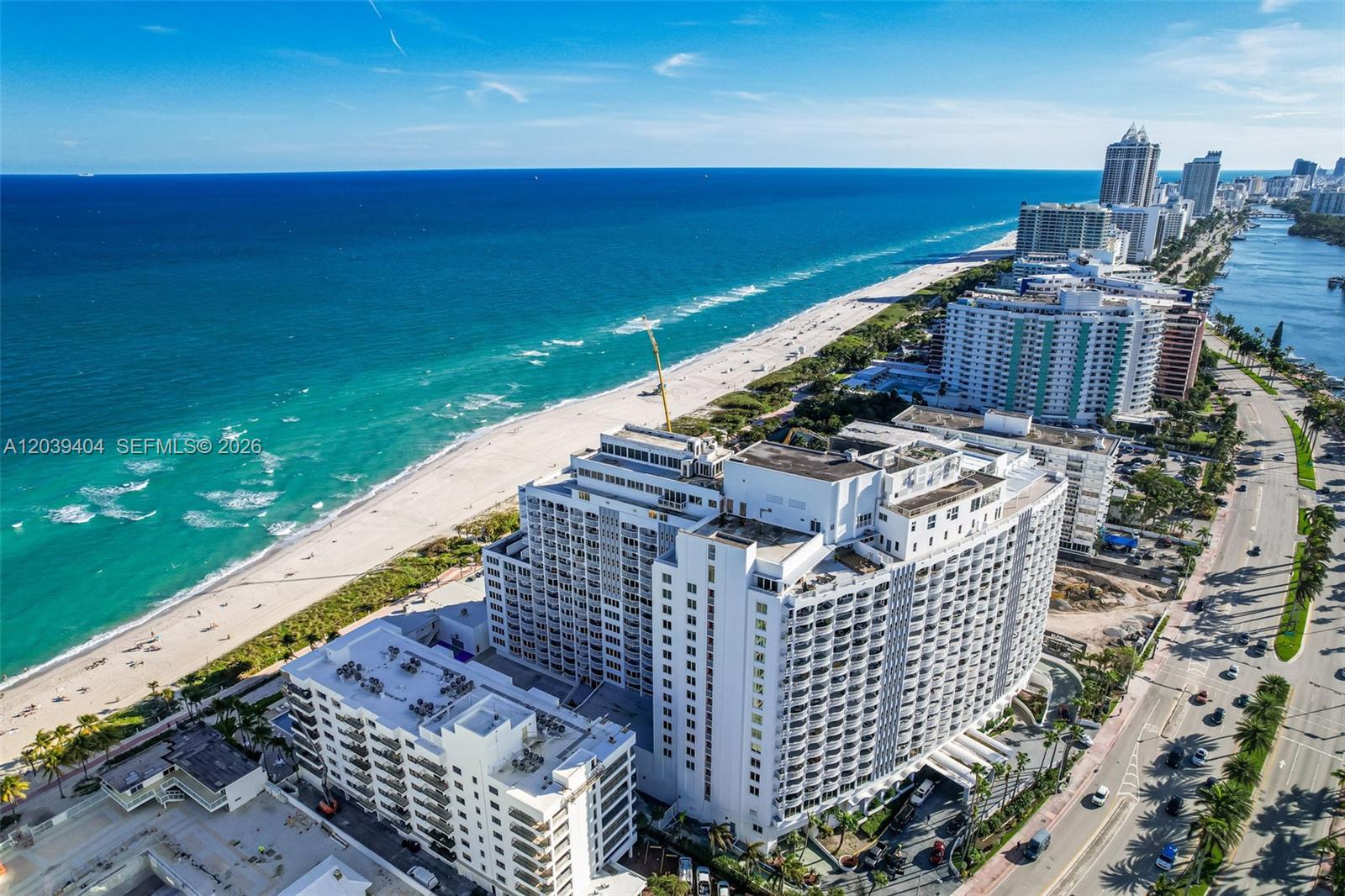 An aerial view shows a large white beachfront condominium complex along a coastal road — 5401 Collins Ave # 813, Miami Beach FL 33140, MIAMI BEACH, FL