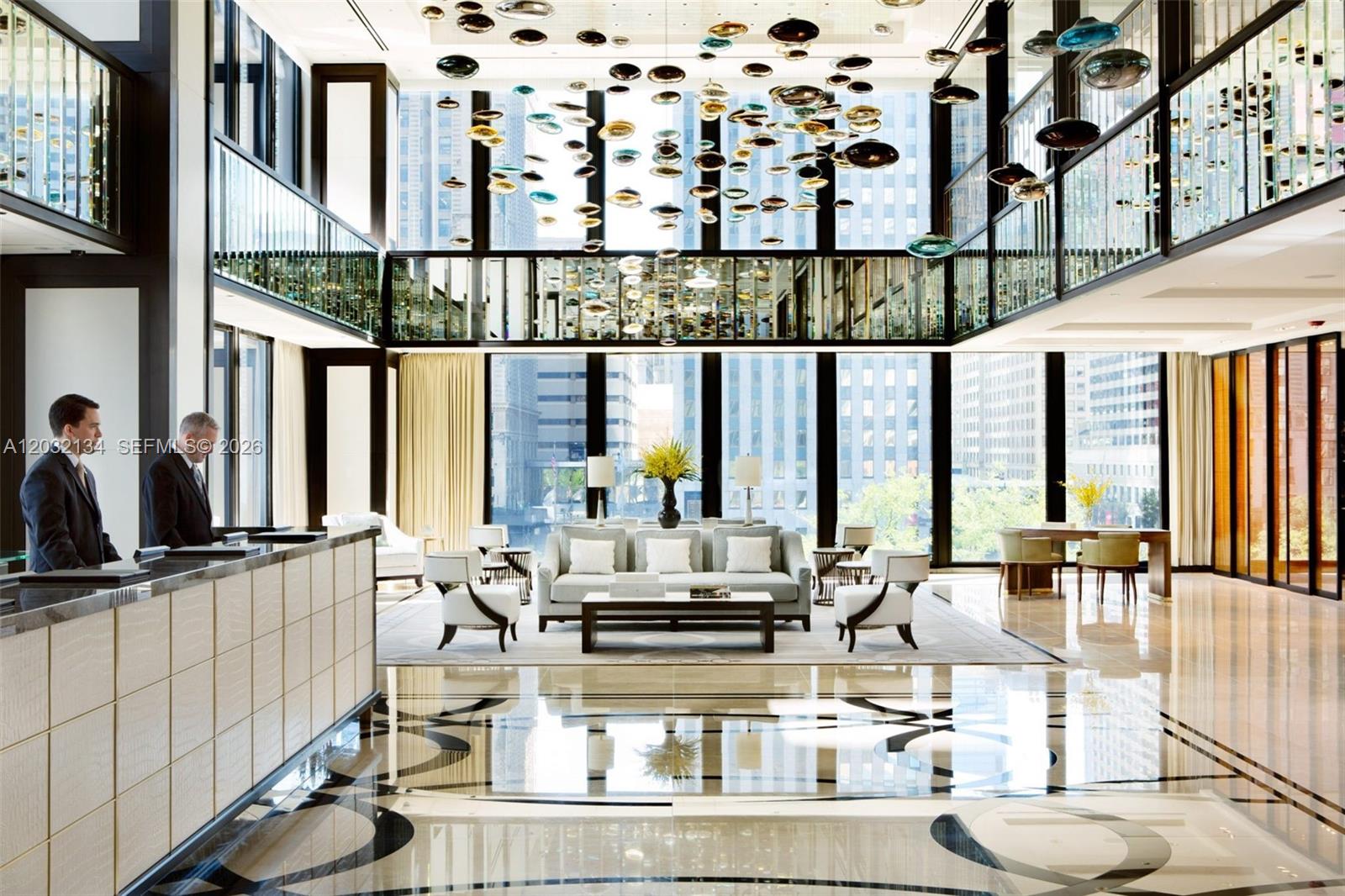 A modern, high-ceilinged hotel lobby features a reception desk, lounge seating, and a glass chandelier — 2301 Collins Ave # 843, Miami Beach FL 33139, MIAMI BEACH, FL