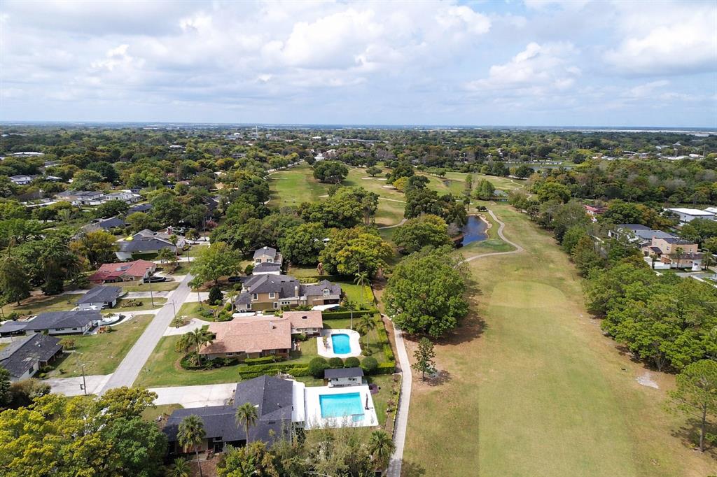 An aerial view shows houses bordering a golf course with two swimming pools in the foreground — 26 BACKSPIN LANE, ORLANDO, FL