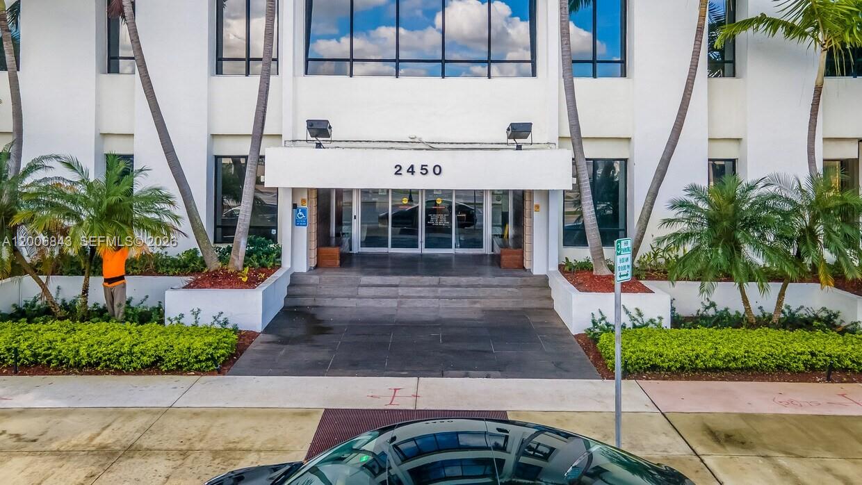 The exterior of a white commercial building features a glass entrance under a numbered canopy — 2450 Hollywood Blvd, Hollywood FL 33020, HOLLYWOOD, FL