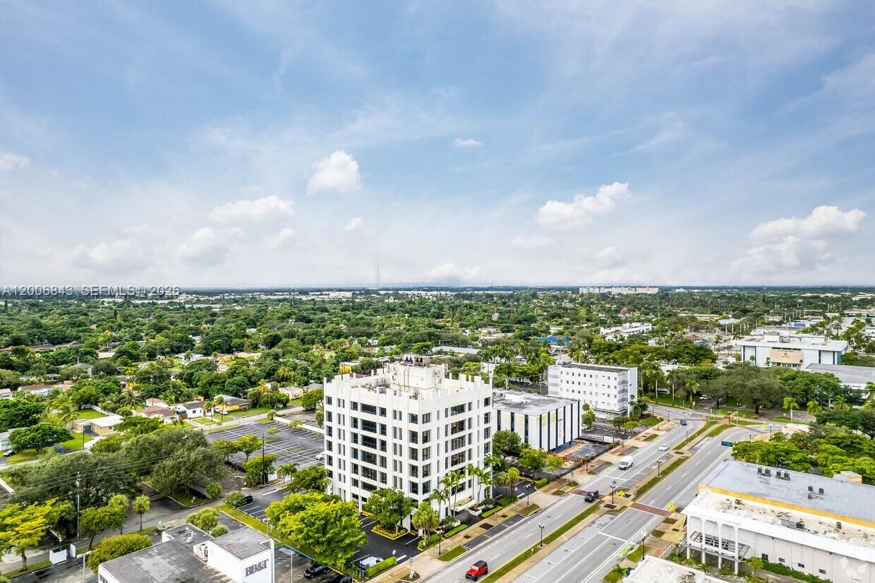 An aerial view shows a multi-story white office building surrounded by trees and roads — 2450 Hollywood Blvd, Hollywood FL 33020, HOLLYWOOD, FL