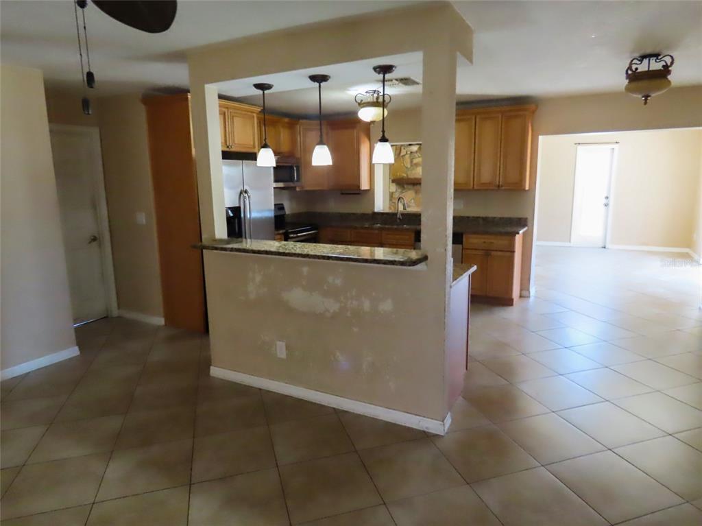 A kitchen with wood cabinets and a breakfast bar overlooks an open living area — 12909 123RD AVENUE, LARGO, FL