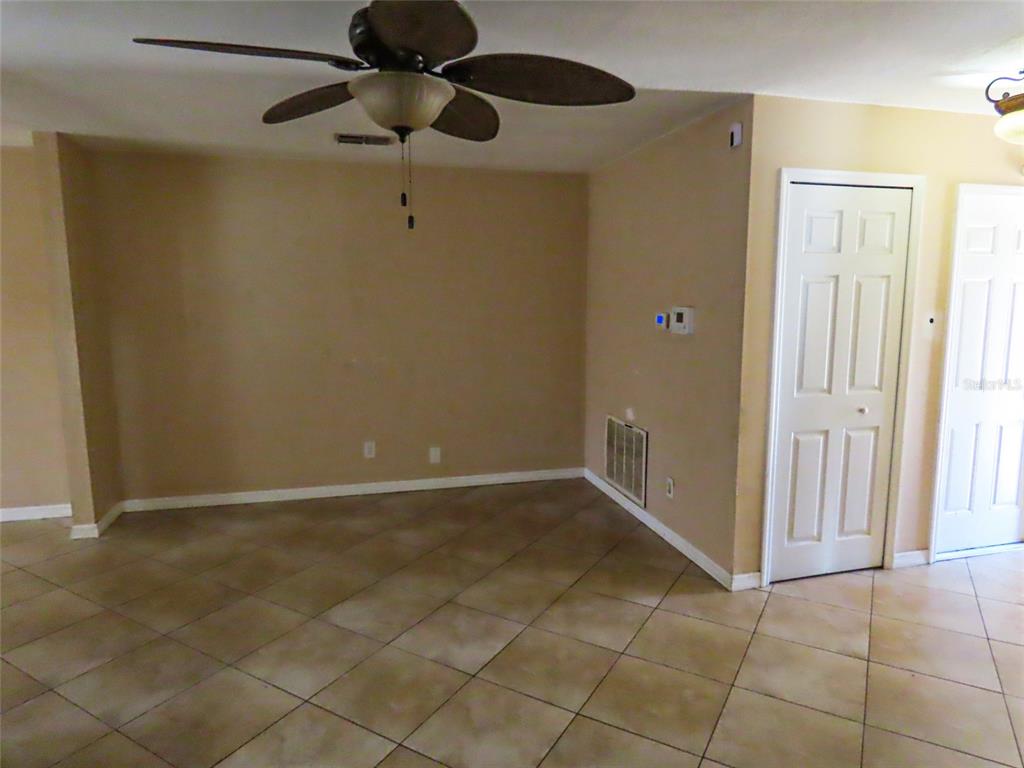 An empty room features tan walls, a ceiling fan, and light-colored tile flooring — 12909 123RD AVENUE, LARGO, FL